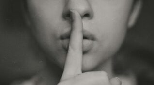Personne qui pose un doigt sur sa bouche pour illustrer les bienfaits du silence